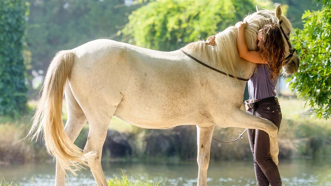 Frau umarmt ihr Pferd und beide sind glücklich